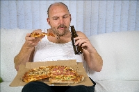 Unhealthy fat man sitting on couch drinking beer and eating pizza