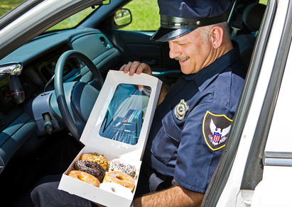 Policeman in his car, hungrily looking at a box of donuts.
