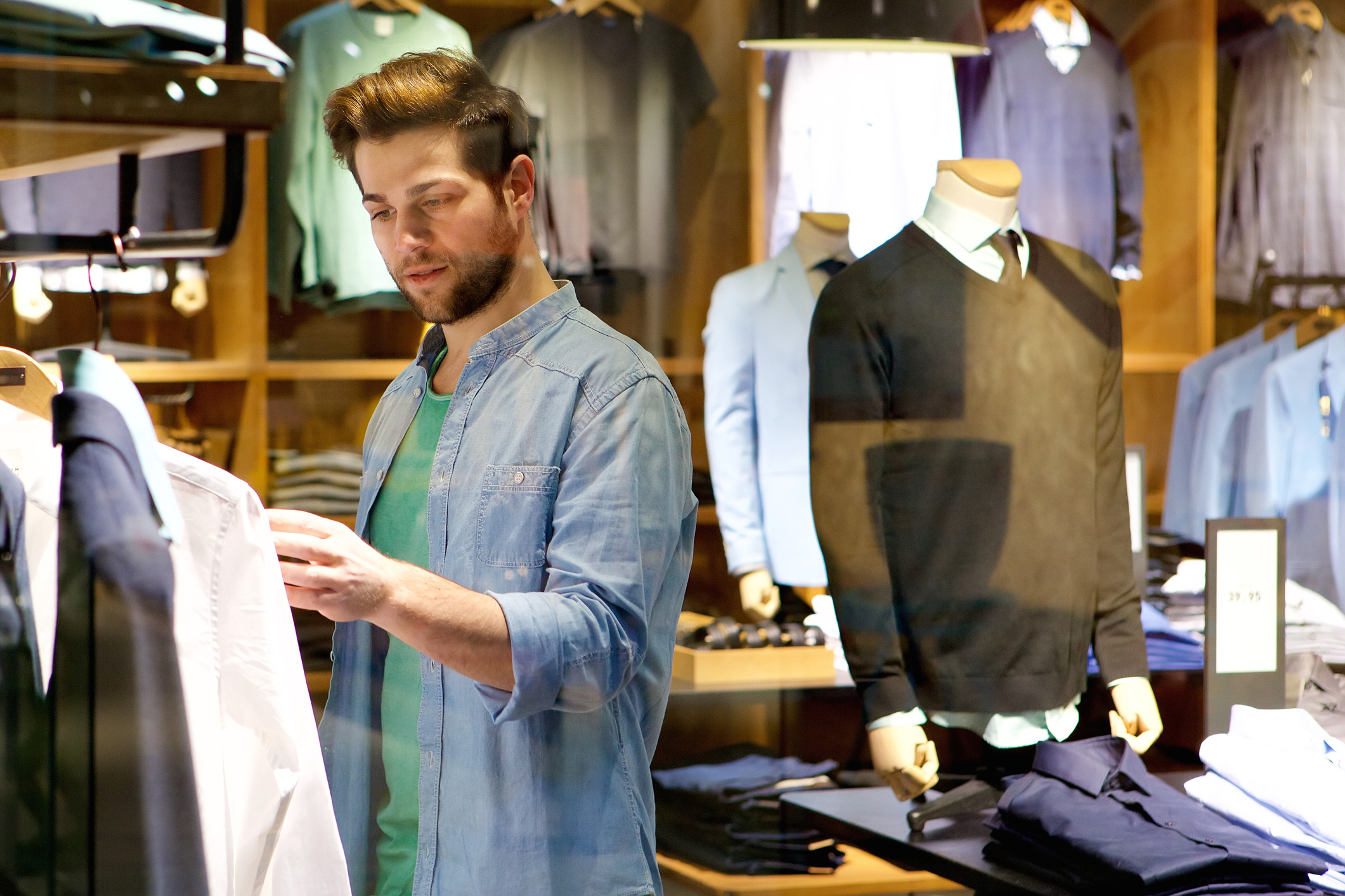 Young man looking at clothes to buy at shop