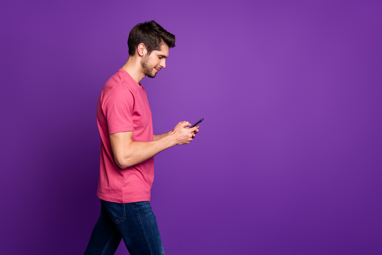 Profile side photo of charming guy go walk copyspace use smartphone have online social media communication with his friends wear pink clothes isolated over bright shine color background