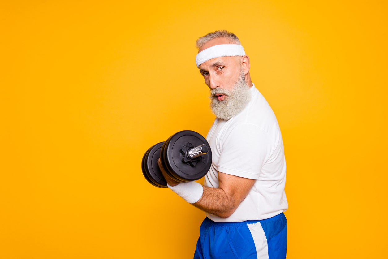 Cool playful flirty naughty strong grandpa with confident grimace exercising holding equipment up, lifts it with strength and power. Body care, fitness, body building, hobby, weight loss lifestyle