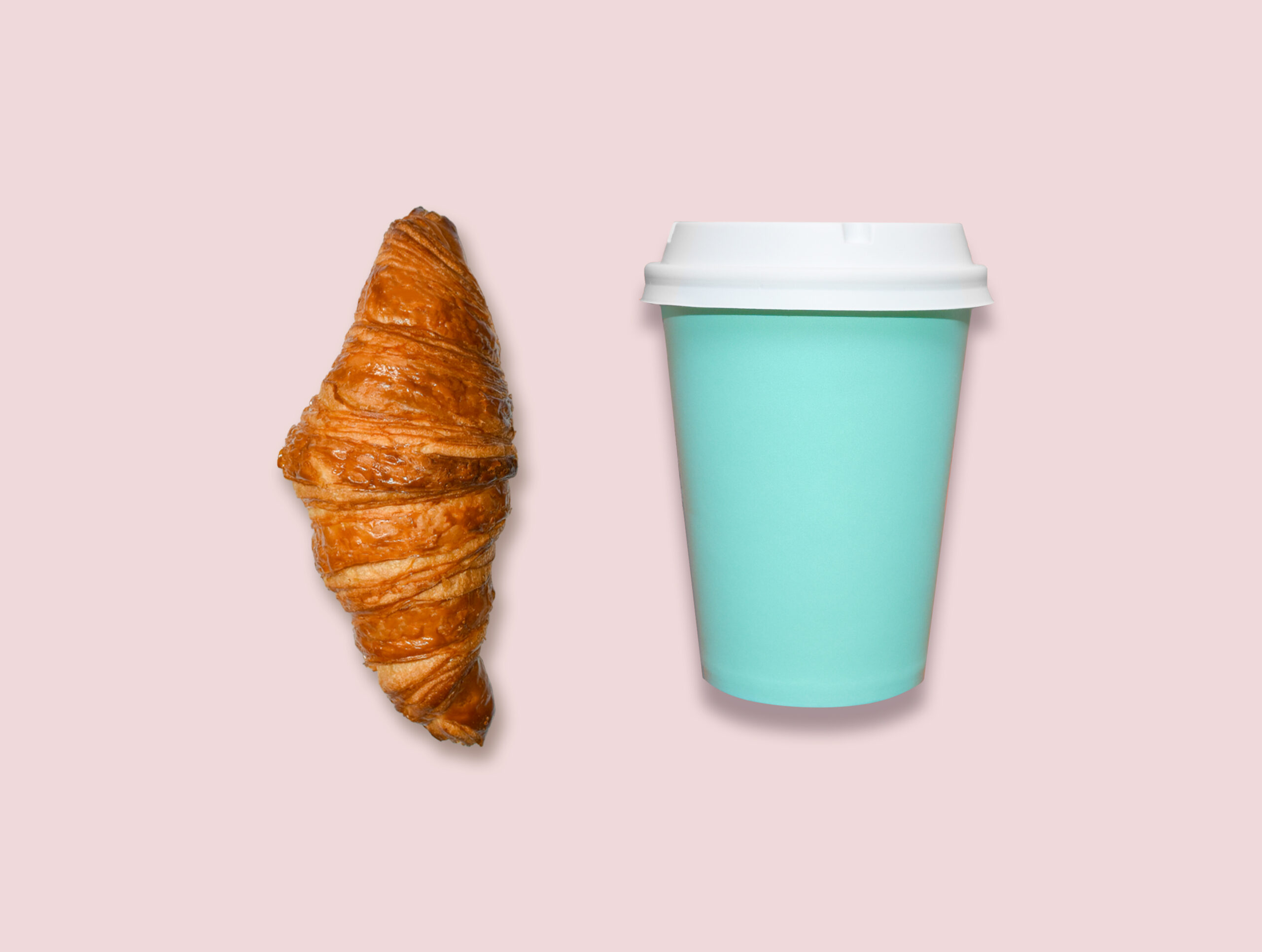Fresh home made croissant and cappuccino take away cup on pink table, top view.