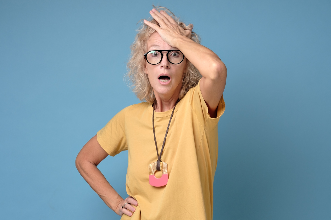 Excited mature blonde woman in glasses holding her head