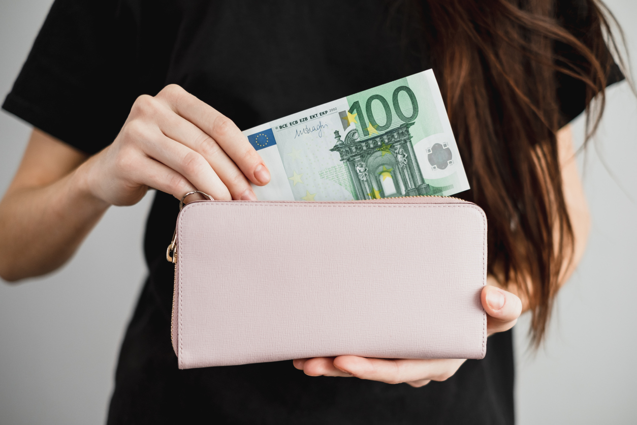 Young woman takes out money euro banknotes from a leather wallet. Close up